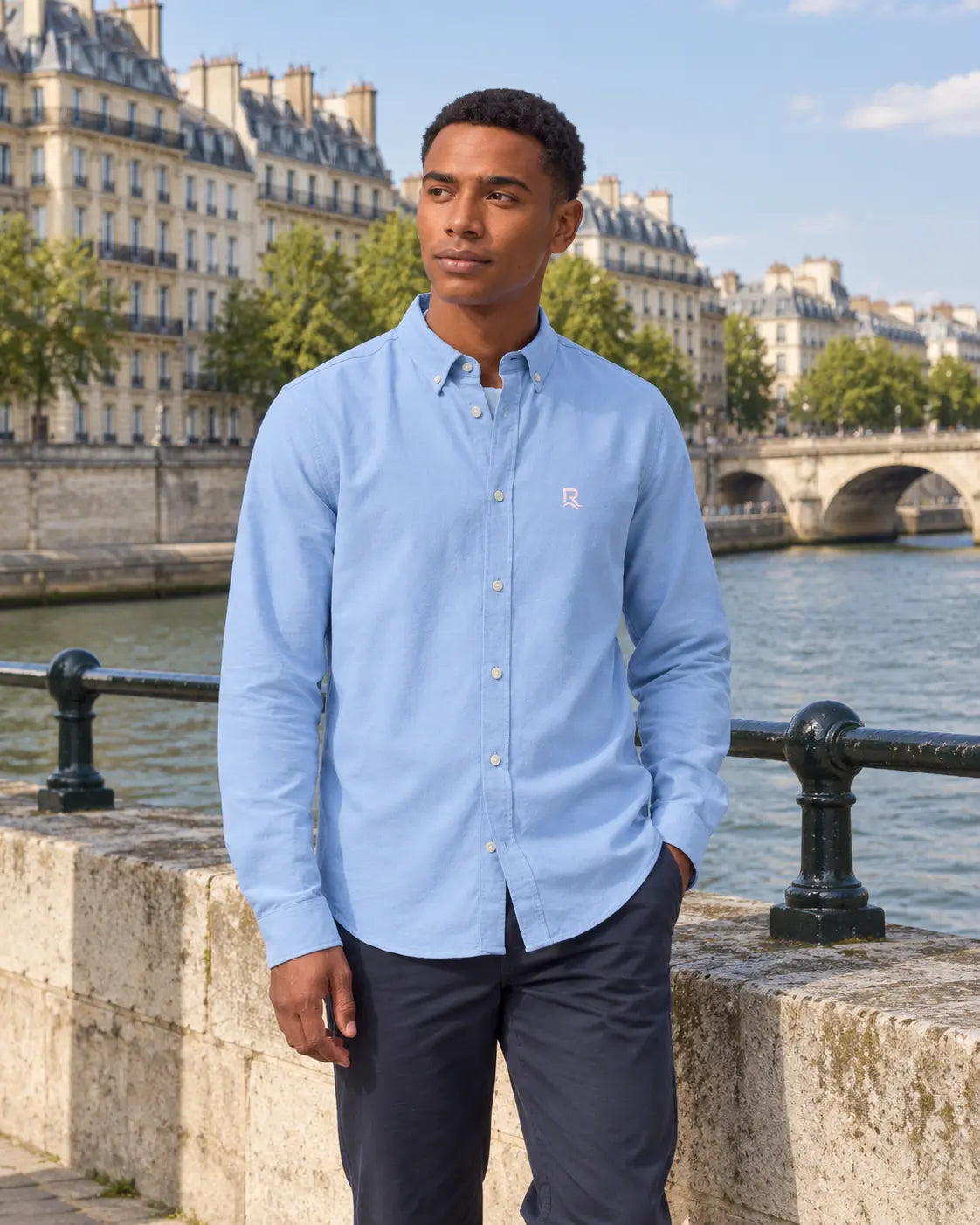Chemise Oxford homme RIVHEX bleu ciel portée, broderie côté cœur, quai en ville