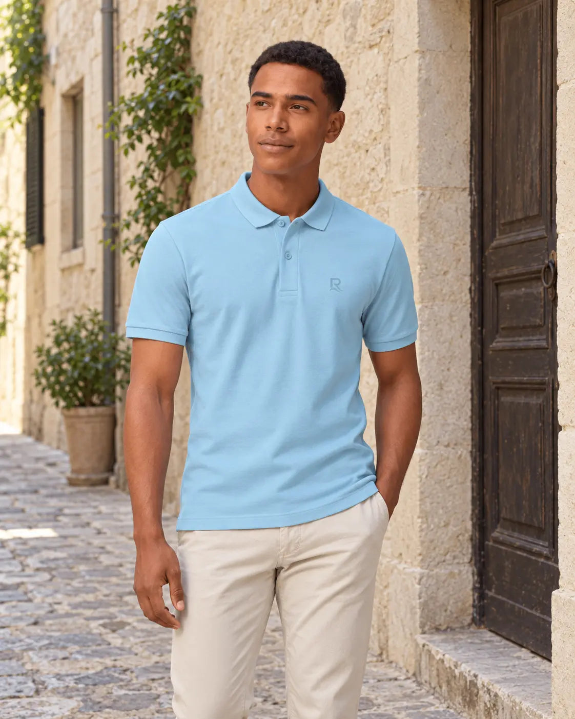 Polo homme RIVHEX bleu ciel porté, broderie ton sur ton, ruelle en pierre