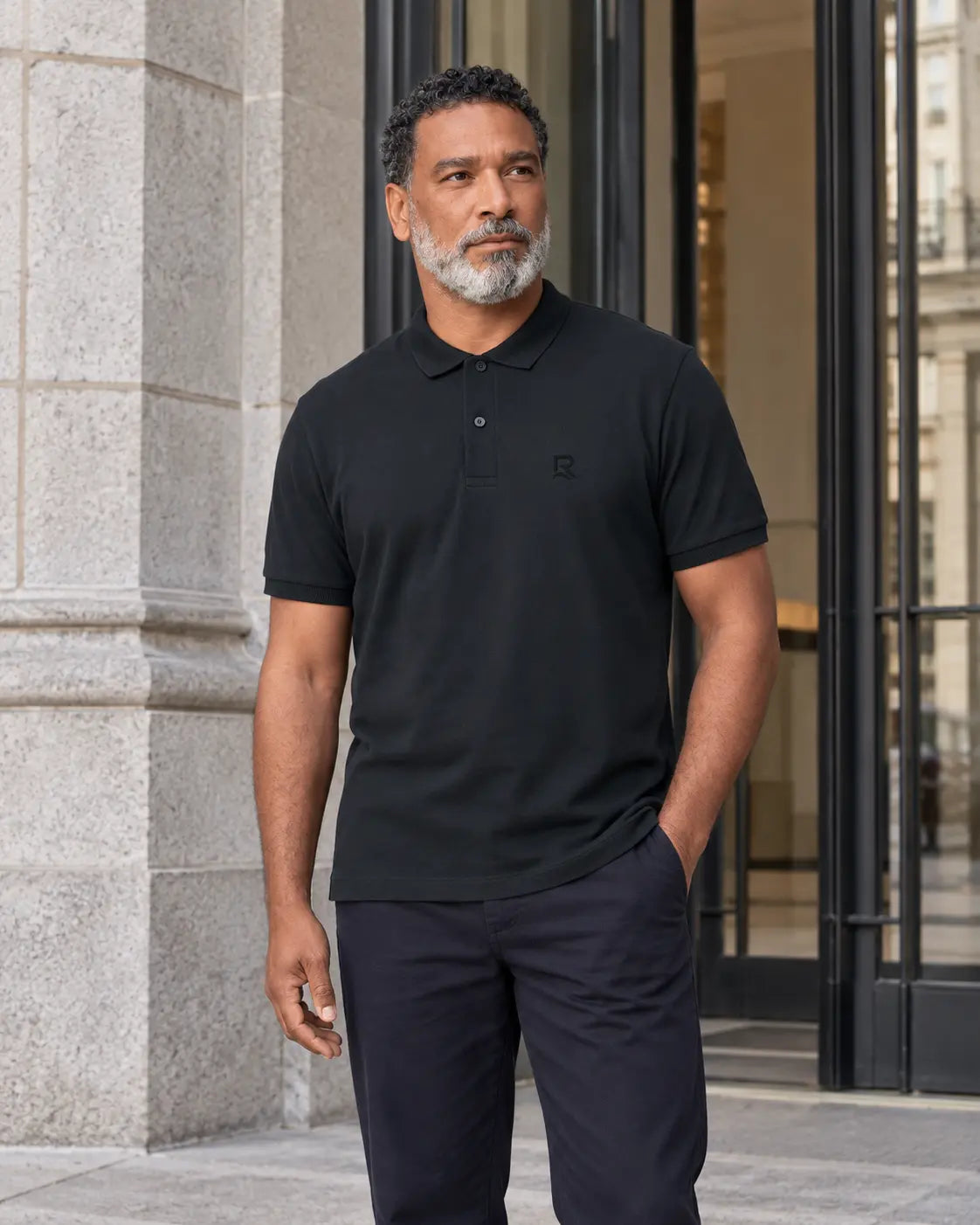 Polo homme RIVHEX noir porté, broderie ton sur ton, architecture contemporaine